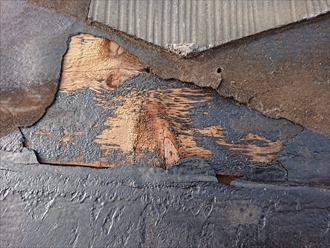 棟板金近くのスレート屋根が剥がれている所。防水紙も剥がれてしまっていて野地板が見えています