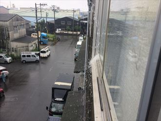 工場雨樋から溢れた雨水が窓に当たっている