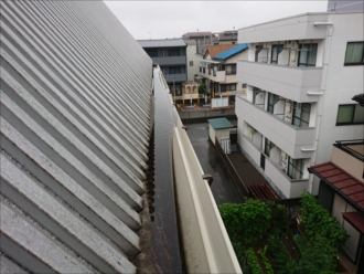 踊り場から見てみると軒樋が雨水の重みで歪んでしまっておりどうやっても竪樋におちないようになっていた