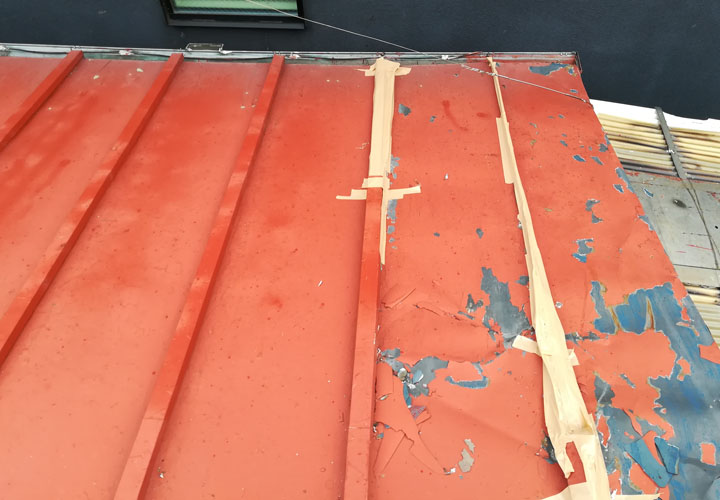 トタン屋根が破損し、瓦棒がテープで補強されている