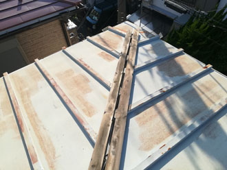 瓦棒葺き屋根の棟板金が飛散し、内部の貫板が露出しています。