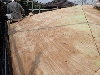 屋根に野地板を増し張りする作業風景