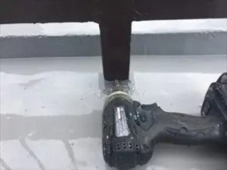鉄骨製の手すりの根元に水抜き穴を作る作業風景