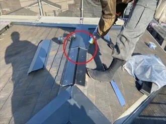 新しいガルバリウム鋼板製の棟板金をビスで固定する作業風景