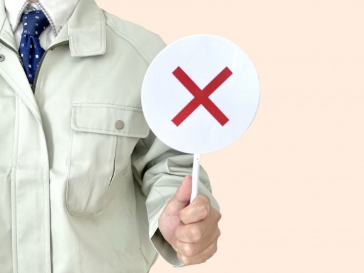 バツ印を掲げる作業員